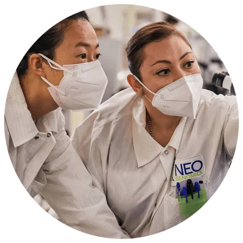 Two NeoGenomics lab employees looking at images on a screen
